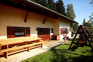 Seitenansicht des Hauses mit großer Sitzgruppe und einer Spielschaukel.