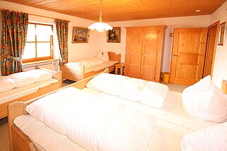 Drittes Schlafzimmer mit einem Doppelbett und zwei Einzelbetten und einem Schrank mit Fenster.